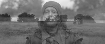 Movie still from “A Field in England” (2013), directed by Ben Wheatley – Double exposure of a man and trees in a field; Medium shot, Low angle