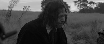 Movie still from “A Field in England” (2013), directed by Ben Wheatley – Black and white photograph of a man with long hair; Medium shot, Over the shoulder angle