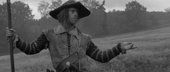 Movie still from “A Field in England” (2013), directed by Ben Wheatley – A black and white photo of a man in a hat; Medium shot, Low angle
