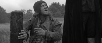 Movie still from “A Field in England” (2013), directed by Ben Wheatley – A black and white photo of a man in a hooded jacket; Medium shot, Over the shoulder angle
