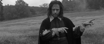 Movie still from “A Field in England” (2013), directed by Ben Wheatley – A black and white photo of a man in a field; Medium shot, Low angle