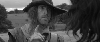 Movie still from “A Field in England” (2013), directed by Ben Wheatley – A person wearing a hat; Close Up shot, Over the shoulder angle