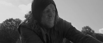 Movie still from “A Field in England” (2013), directed by Ben Wheatley – A black and white photo of a man with long hair; Close Up shot, Over the shoulder angle