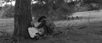 Movie still from “A Field in England” (2013), directed by Ben Wheatley – A man is sitting on the ground while another man is sitting on the ground; Wide shot, High angle