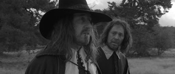 Movie still from “A Field in England” (2013), directed by Ben Wheatley – A man with a long beard and a man with long hair and a hat; Medium shot, Over the shoulder angle