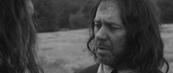 Movie still from “A Field in England” (2013), directed by Ben Wheatley – Black and white photograph of a man with long hair; Close Up shot, Over the shoulder angle