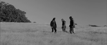 Movie still from “A Field in England” (2013), directed by Ben Wheatley – A group of people standing on top of a grass covered field; Wide shot, Low angle