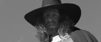 Movie still from “A Field in England” (2013), directed by Ben Wheatley – A black and white photo of a man wearing a hat; Close Up shot, Low angle