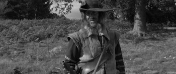 Movie still from “A Field in England” (2013), directed by Ben Wheatley – A black and white photo of a man with a long beard; Medium shot, Over the shoulder angle