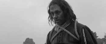 Movie still from “A Field in England” (2013), directed by Ben Wheatley – Black and white photograph of a man with long hair; Close Up shot, Low angle