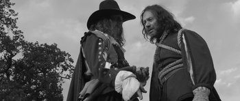 Movie still from “A Field in England” (2013), directed by Ben Wheatley – Two men dressed in medieval clothing talking to each other; Medium shot, Over the shoulder angle