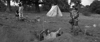 Movie still from “A Field in England” (2013), directed by Ben Wheatley – An old photo of a man laying in a hole in the ground; Wide shot, High angle