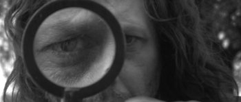 Movie still from “A Field in England” (2013), directed by Ben Wheatley – A person's eye with a magnifying glass; Extreme Close Up shot, High angle