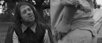 Movie still from “A Field in England” (2013), directed by Ben Wheatley – A black - and - white photo of a man with a beard; Medium shot, Over the shoulder angle
