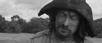 Movie still from “A Field in England” (2013), directed by Ben Wheatley – A person wearing a hat; Close Up shot, Over the shoulder angle