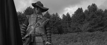 Movie still from “A Field in England” (2013), directed by Ben Wheatley – A black and white photo of a man in a hat; Medium shot, Low angle