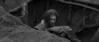 Movie still from “A Field in England” (2013), directed by Ben Wheatley – A black and white photo of a man in a cave; Wide shot, High angle