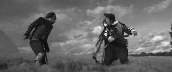Movie still from “A Field in England” (2013), directed by Ben Wheatley – Two people in a field with clouds in the background; Wide shot, Low angle