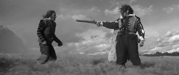 Movie still from “A Field in England” (2013), directed by Ben Wheatley – Two men are fighting over a gun in a field; Wide shot, Low angle