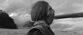 Movie still from “A Field in England” (2013), directed by Ben Wheatley – Black and white photograph of a man smoking a pipe; Close Up shot, Low angle