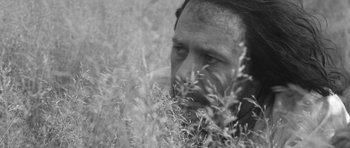Movie still from “A Field in England” (2013), directed by Ben Wheatley – A black - and - white photo of a man in tall grass; Close Up shot, High angle