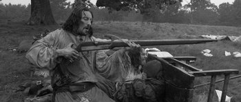 Movie still from “A Field in England” (2013), directed by Ben Wheatley – A black - and - white photo of a man and woman in a boat; Medium shot, Over the shoulder angle