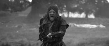 Movie still from “A Field in England” (2013), directed by Ben Wheatley – A man in medieval garb with a sword in his hand; Medium shot, Low angle
