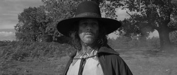 Movie still from “A Field in England” (2013), directed by Ben Wheatley – A black and white photo of a man wearing a hat; Medium shot, Low angle