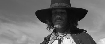 Movie still from “A Field in England” (2013), directed by Ben Wheatley – A black and white photo of a man wearing a hat; Close Up shot, Low angle