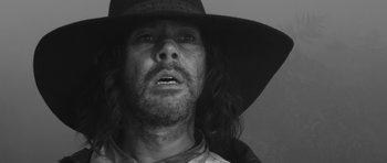 Movie still from “A Field in England” (2013), directed by Ben Wheatley – A black and white photo of a man with long hair wearing a cowboy hat; Close Up shot, Low angle