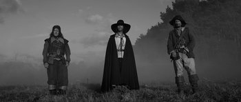 Movie still from “A Field in England” (2013), directed by Ben Wheatley – A man wearing a black hat and a long cape; Medium shot, Low angle