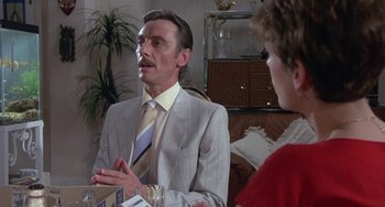 Movie still from “A Fish Called Wanda” (1988), directed by Charles Crichton – A man in a suit and tie talking to a woman; Medium shot, Over the shoulder angle
