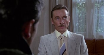 Movie still from “A Fish Called Wanda” (1988), directed by Charles Crichton – A man in a suit and tie looking into a mirror; Close Up shot, Over the shoulder angle