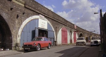 Movie still from “A Fish Called Wanda” (1988), directed by Charles Crichton – An old car parked in front of an old building; Extreme Wide shot, Low angle