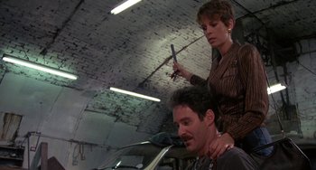 Movie still from “A Fish Called Wanda” (1988), directed by Charles Crichton – A man getting his hair cut by a woman in a garage; Medium shot, Low angle