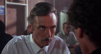 Movie still from “A Fish Called Wanda” (1988), directed by Charles Crichton – An older man in a white dress shirt is looking at the camera; Close Up shot, Over the shoulder angle