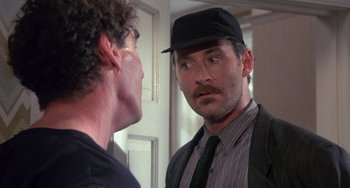 Movie still from “A Fish Called Wanda” (1988), directed by Charles Crichton – A man wearing a hat and a tie looking at himself in the mirror; Close Up shot, Over the shoulder angle