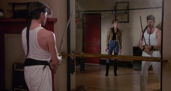 Movie still from “A Fish Called Wanda” (1988), directed by Charles Crichton – Two people in a room with a mirror; Wide shot, Over the shoulder angle