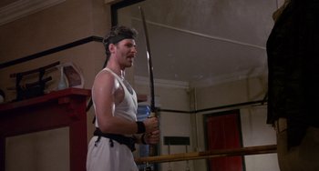 Movie still from “A Fish Called Wanda” (1988), directed by Charles Crichton – A man holding a pair of swords in his hands; Medium shot, Low angle