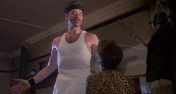 Movie still from “A Fish Called Wanda” (1988), directed by Charles Crichton – A man in a white tank top is talking to a woman in leopard print; Medium shot, Low angle