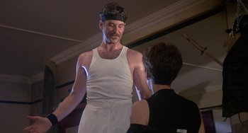 Movie still from “A Fish Called Wanda” (1988), directed by Charles Crichton – A man in a white tank top is talking to a woman; Medium shot, Low angle