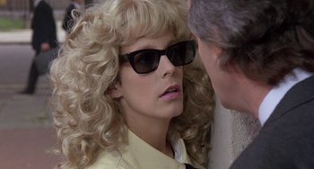 Movie still from “A Fish Called Wanda” (1988), directed by Charles Crichton – A woman wearing sunglasses talking to a man wearing a suit; Close Up shot, Over the shoulder angle
