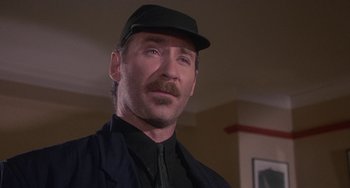 Movie still from “A Fish Called Wanda” (1988), directed by Charles Crichton – A person wearing a hat and a jacket; Close Up shot, Low angle