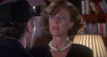 Movie still from “A Fish Called Wanda” (1988), directed by Charles Crichton – A woman wearing a pearl necklace talking to a man in a hat; Close Up shot, Over the shoulder angle