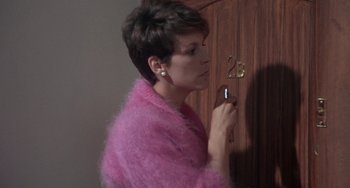 Movie still from “A Fish Called Wanda” (1988), directed by Charles Crichton – A woman in a pink sweater is looking at a door; Medium shot, Over the shoulder angle