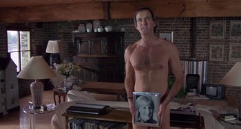 Movie still from “A Fish Called Wanda” (1988), directed by Charles Crichton – A naked man holding a picture in a living room; Medium shot, High angle