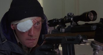 Movie still from “A Fish Called Wanda” (1988), directed by Charles Crichton – A man with a bandage on his eye is looking at a rifle; Close Up shot, Over the shoulder angle