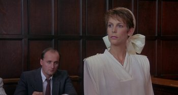 Movie still from “A Fish Called Wanda” (1988), directed by Charles Crichton – A man and a woman sitting in front of a wooden wall; Medium shot, Low angle