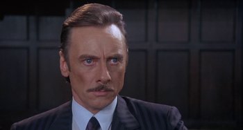 Movie still from “A Fish Called Wanda” (1988), directed by Charles Crichton – A person wearing a suit and tie; Close Up shot, Over the shoulder angle