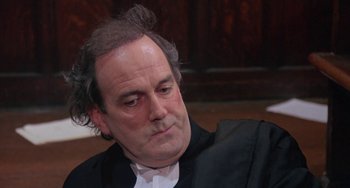 Movie still from “A Fish Called Wanda” (1988), directed by Charles Crichton – A man in a black jacket and white shirt; Close Up shot, High angle